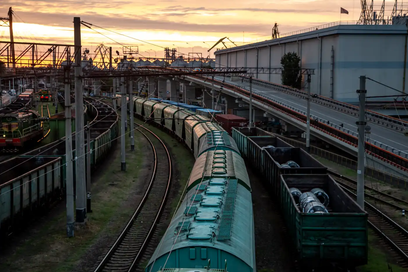 Freight trains in a rail yard at sunset seen from a bridge