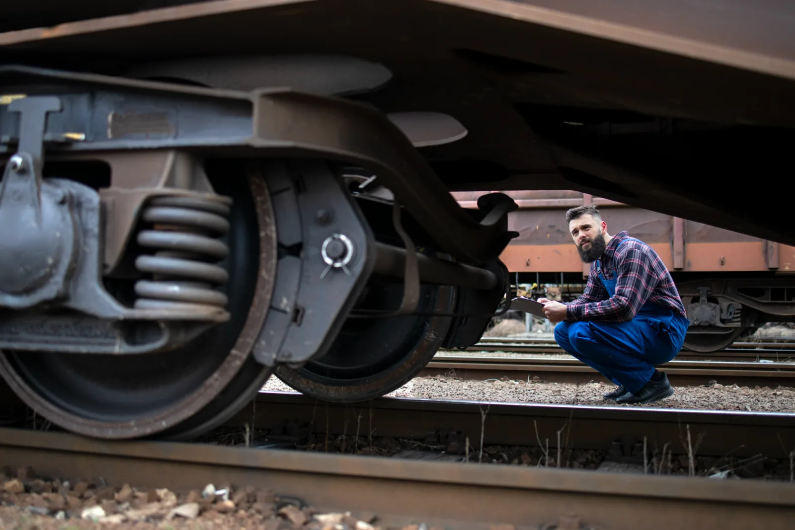 Railroad worker inspecting the wheels and brakes of a freight car
